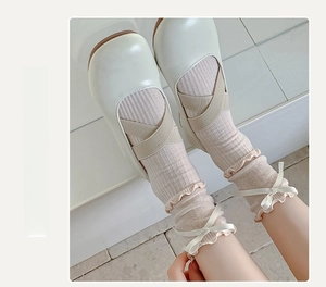 Close-up of light pink ruffle socks with cream ribbon bows and Mary Jane shoes