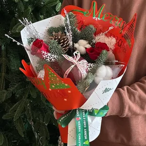Christmas bouquet with red roses, apple, and pine cones in festive red and white packaging