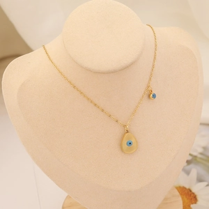 Détail du collier mauvais œil doré avec pendentif goutte sur support en velours