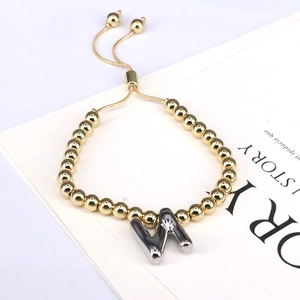 Close-up of golden beaded adjustable bracelet with silver W initial balloon charm