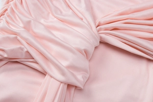 Close-up of pink satin fabric showing smooth texture and elegant knotted drape detail