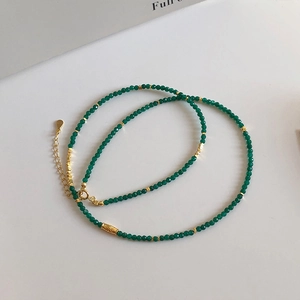 Detail view of a fine green beaded necklace with gold spacers and lobster clasp
