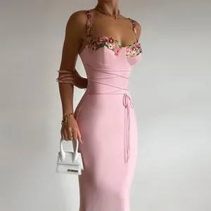 Close-up of pink floral embroidery and cross-strap waist design on a sexy midi dress
