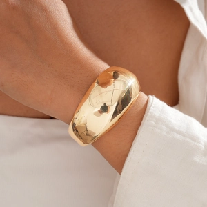 Macro detail of high-polish 18k gold plated wide cuff bracelet on wrist