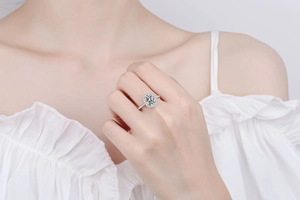 Detail of oval moissanite ring with halo setting on finger in soft lighting
