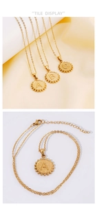 Close-up of 18K gold-plated coin letter pendants with textured finish and beaded edges