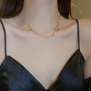 Detail of a minimalist gold choker necklace with delicate leaf charms on female model