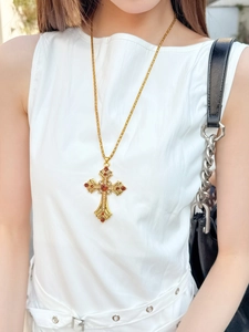 Collier croix gothique dorée avec strass ambrés porté par un mannequin chic