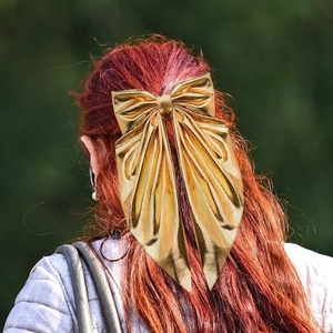 Elegant gold metal bow hair clip with long ribbons worn on red hair back view