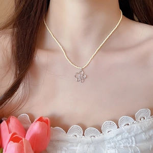 Dettaglio della collana di perle gialle con un delicato ciondolo a fiore in argento