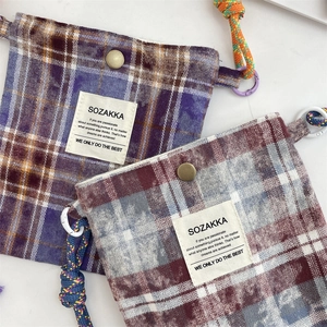 Close-up of vintage plaid canvas mini bags with retro metal snaps and colorful braided cords