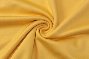 Détail de la texture du tissu jaune montrant les plis doux et le drapé