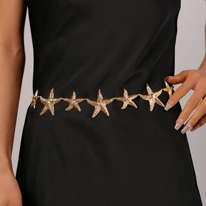 Detail of vintage gold starfish waist chain with textured metal relief on a black dress