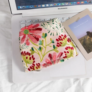 Top view of a floral jacquard makeup bag with a metal zipper on a laptop keyboard