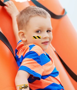 Luminous construction vehicle temporary tattoos on a boy's arm and face