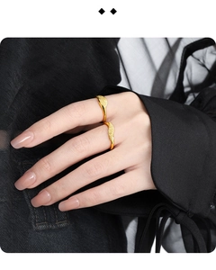 Macro detail of two matte gold irregular wavy textured rings worn on person finger