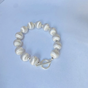 Détail du collier à perles argentées brossées avec un fermoir à bascule en T de style rétro