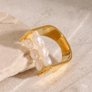 Macro di un anello martellato in oro 18k con perle bianche su uno sfondo di pietra naturale
