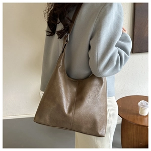 Detailed shoulder view of a brown textured faux leather tote bag on a model