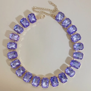Detailed close-up of a purple rectangular crystal necklace with a golden chain clasp