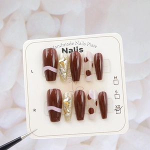 Vue détaillée de faux ongles faits main marron et rose avec paillettes et strass