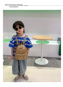 Kids khaki canvas backpack shown on a child model for size and fit reference