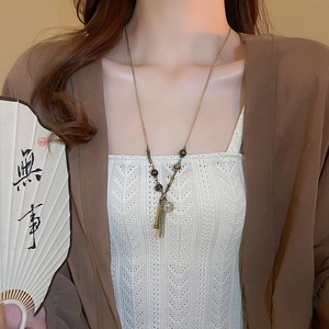 Dettaglio della collana di perle vintage con nappe metalliche e monete