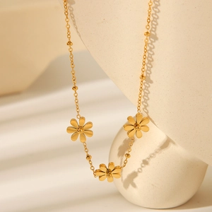 Close-up of golden sunflower pendant necklace with beads on a beige display stand