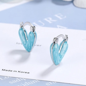 Silver heart earrings with light blue marble enamel finish on a display card