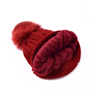 Women's burgundy knit beanie with a large faux fur pompom and warm fleece lining