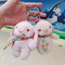 Detail of cute plush astronaut rabbit keychains in pink and beige with plaid scarves