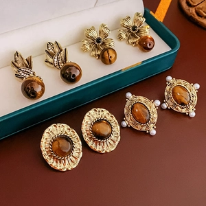 Gros plan de boucles d'oreilles vintage en or avec pierres œil de tigre et perles sur boîte