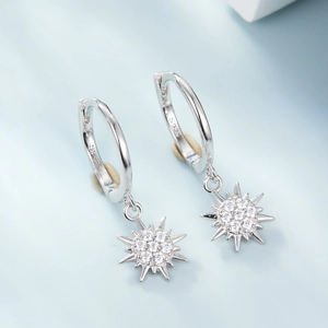 Macro detail of S925 sterling silver hoop earrings with sparkling zircon star pendants