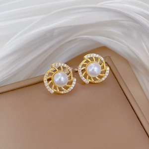 Detailed close-up of golden spiral pearl earrings with crystal accents on silk fabric