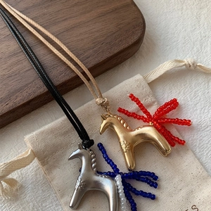 Detail of horse pendant necklaces with beaded tassels on woven cords and wood tray