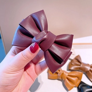Gros plan sur une pince à cheveux nœud en cuir PU vintage avec une texture bordeaux