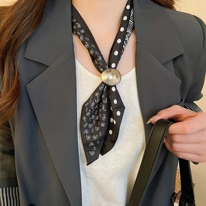 Close-up of silk scarf with paisley and polka dot patterns with metal ring accessory