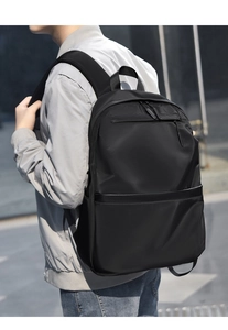 Modern black minimalist backpack on model showing large capacity for laptop use