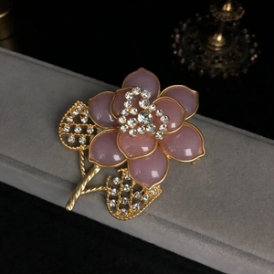 Nahaufnahme der rosa Emaille-Blumenbrosche mit Goldrand und funkelnden Kristallen