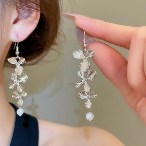 Detail of silver metal flower drop earrings with white pearls in a minimalist elegant design