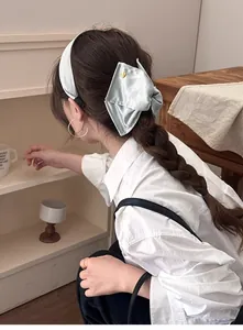 Détail d'un serre-tête en soie vert menthe avec nœud et bouton doré sur modèle