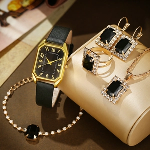 Macro shot of luxury gold watch with black leather strap and matching jewelry set