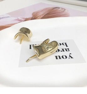 Detailed view of irregular curved gold earring on a minimalist decorative display tray