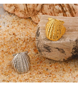 Macro shot of gold and silver shell-shaped rings with metal texture on sandy rock