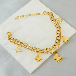 Gold butterfly double-layered bracelet with delicate charms on elegant marble background
