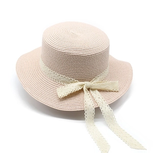 Detailed view of breathable woven straw hat with delicate white lace bow and wavy brim