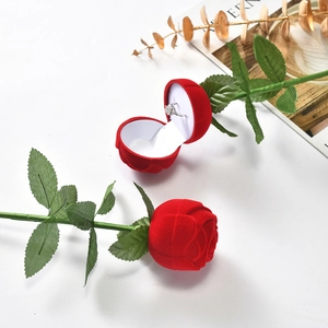 Detailed top view of a red rose ring box with a green stem and a diamond ring inside