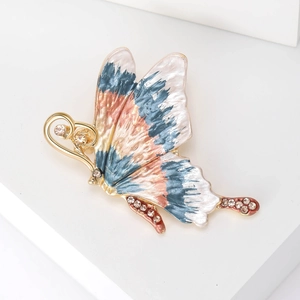 Macro detail of enamel butterfly brooch with colorful gradients and crystal inlay