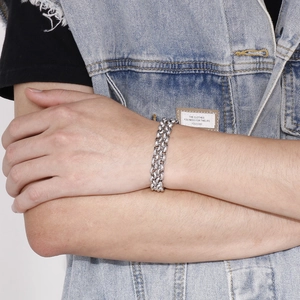 Gros plan du bracelet gourmette argentée à double rangée sur mannequin en jean