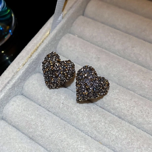 Gros plan de boucles d'oreilles cœur avec cristaux sombres sur plateau en velours gris